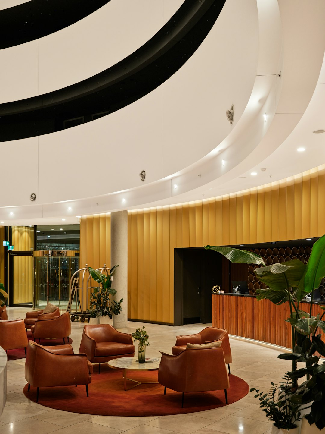 Lobby d'hôtel moderne avec des fauteuils en cuir autour d'un tapis rouge.