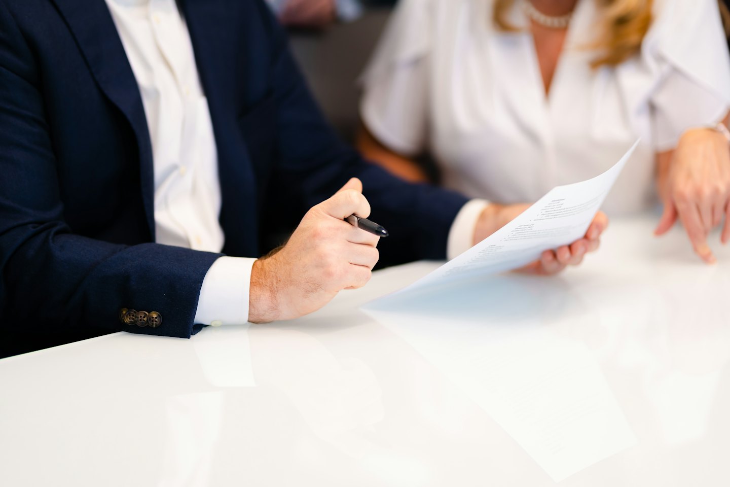 Un homme et une femme examinent un document à une table blanche.